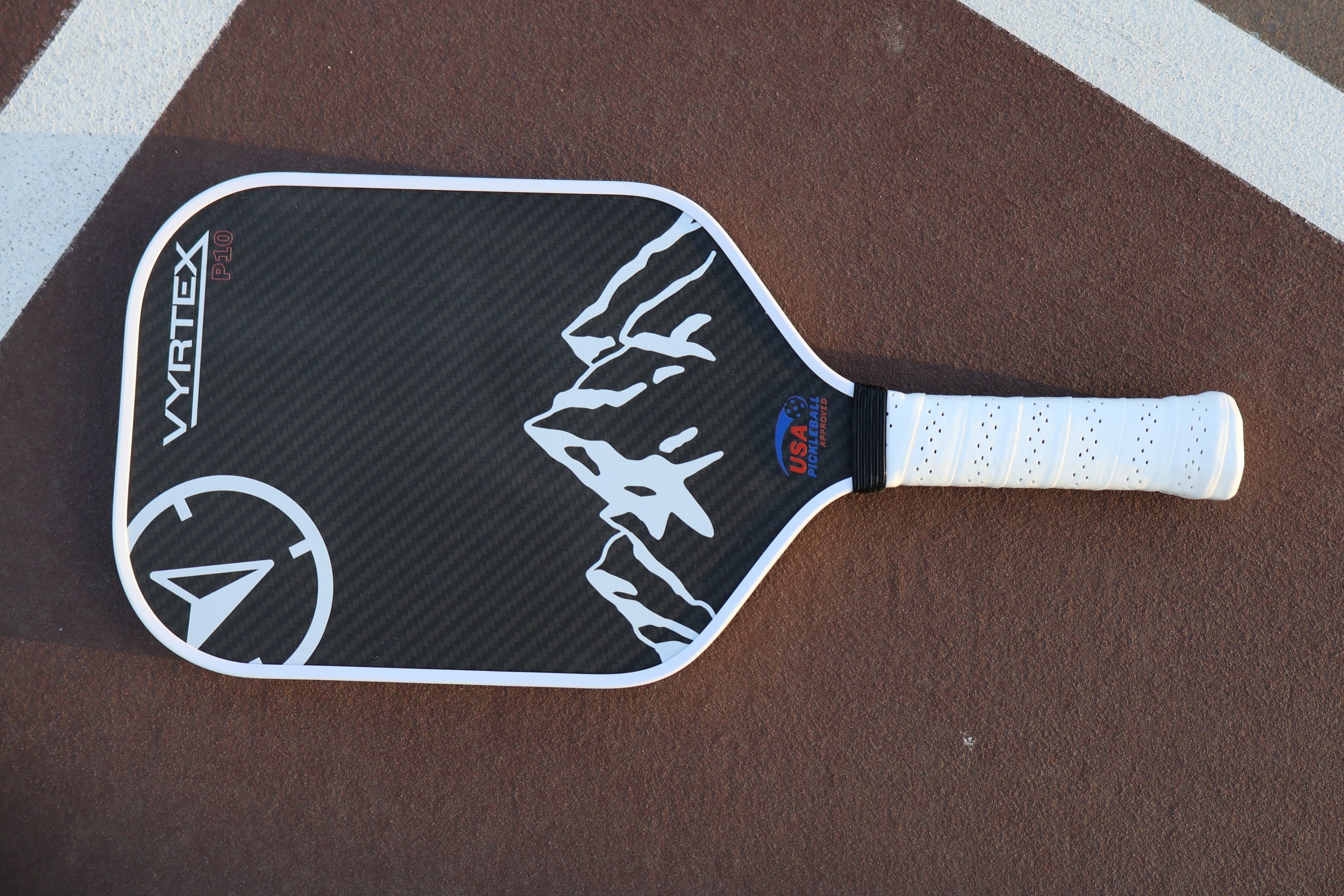 Vyrtex carbon fiber paddle sitting cinematically on a pickleball court at sundown