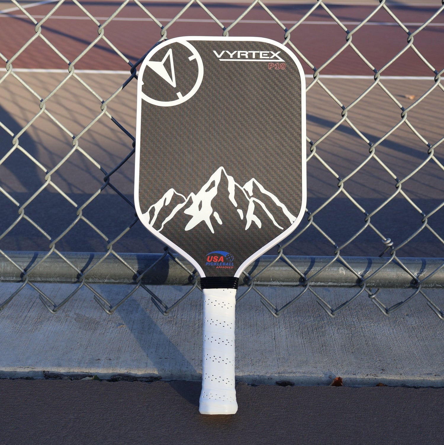 Vyrtex Carbon Fiber Paddle set up against a fence at dusk. 